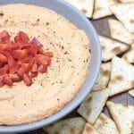 Close up view of roasted red pepper hummus in a bowl.