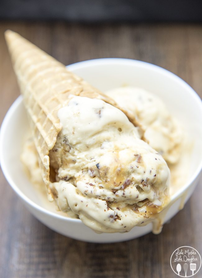 A bowl of caramel ice cream with a waffle cone sticking on top of it.