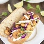 Front view of shrimp sandwich with cilantro lime cabbage slaw on a plate.