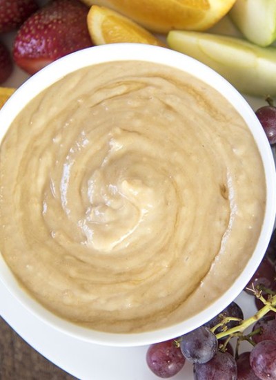 Above view of honey peanut butter yogurt dip in a white bowl with fruit.