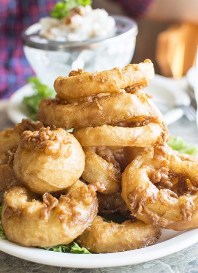 A stack of onion rings on a white plate.