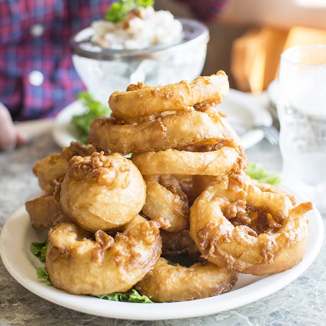 A stack of onion rings on a white plate.