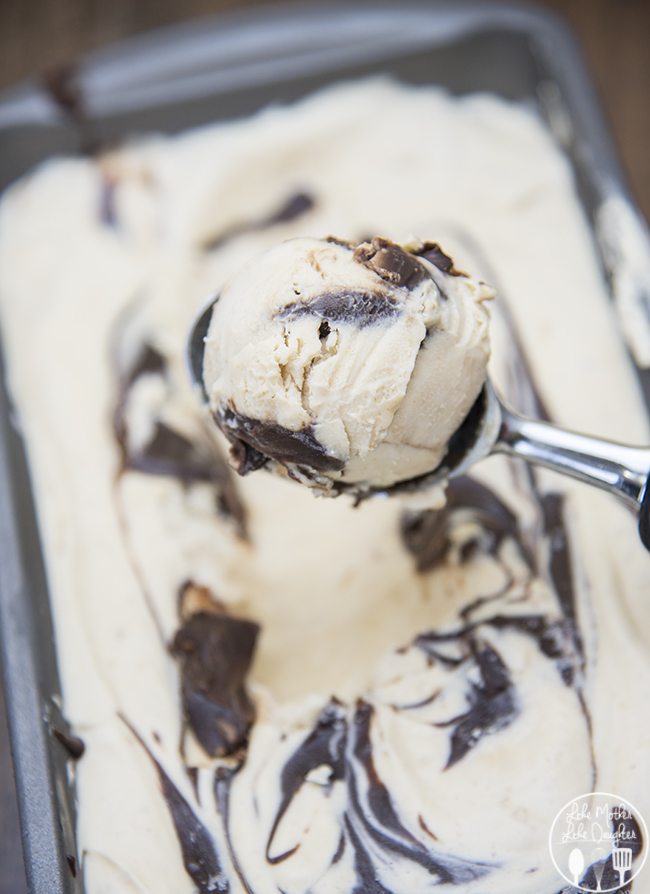 A scoopful of peanut butter and fudge ice cream above a container of it. 