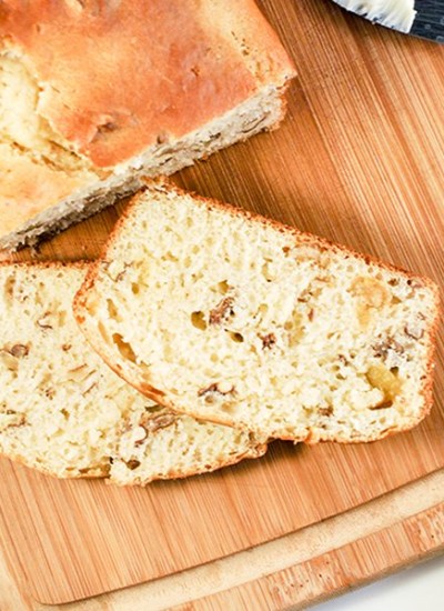 Above view of slices of orange pecan bread slices and loaf on wood board.