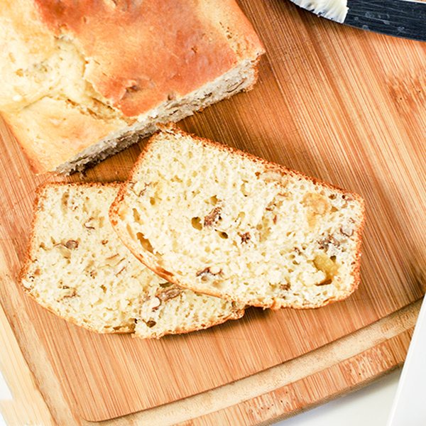Above view of slices of orange pecan bread slices and loaf on wood board.