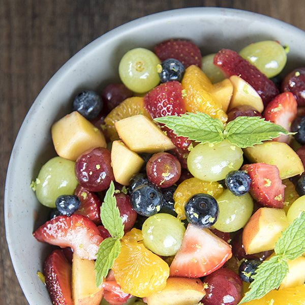 Above view of rainbow fruit salad in a white bowl.