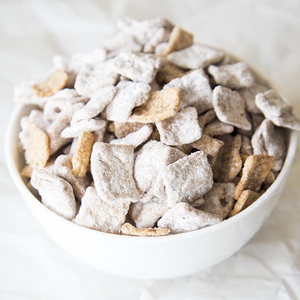 Angled view of snickerdoodle muddy buddies in a white bowl.