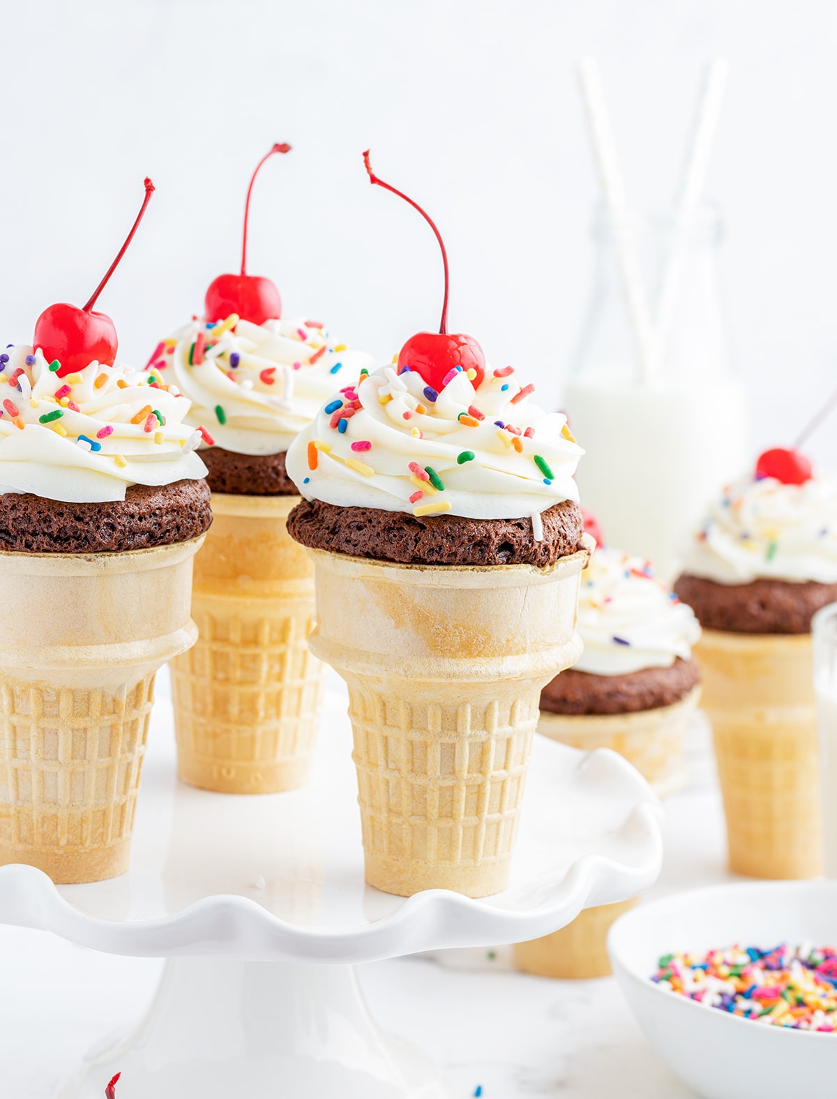 Chocolate cupcakes baked in ice cream cones and topped with frosting to look like an ice cream cone with a cherry on top.