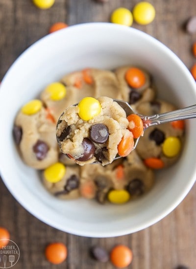 A spoonful of peanut butter cookie dough with reeses pieces and chocolate chips in it.