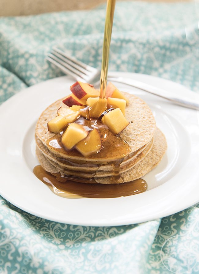 Angled view of biggest loser pancakes stacked on a white plate with syrup being poured on top.