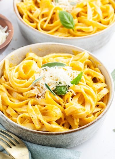 A bowl of butternut squash fettucine pasta topped with parmesan cheese.
