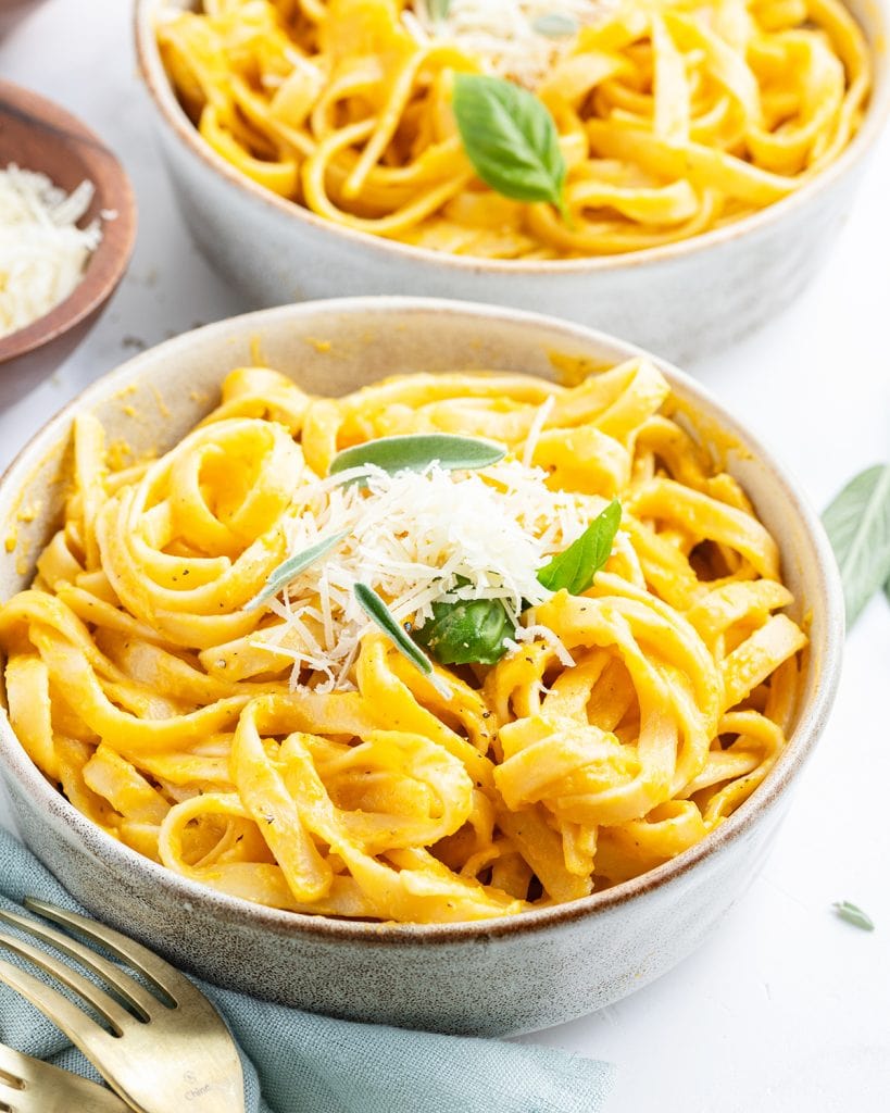 A bowl of butternut squash fettucine pasta topped with parmesan cheese.