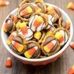 Angled view of candy corn pretzel treats in an orange bowl.