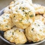 Angled view of cheddar bay biscuits stacked in a grey bowl.