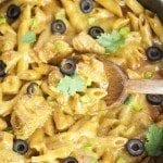 Top view of one pot chicken enchilada pasta with a wooden spoon.