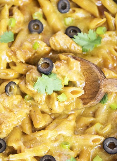 Top view of one pot chicken enchilada pasta with a wooden spoon.