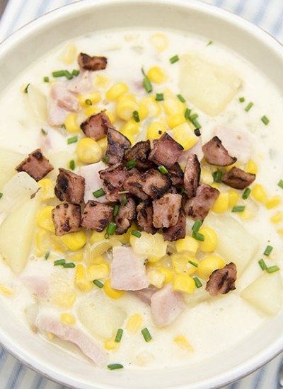 Top view of corn, ham, and potato chowder in a white bowl.