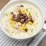 Top view of corn, ham, and potato chowder in a white bowl.