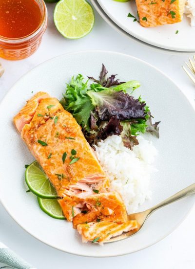 An overhead photo of a salmon fillet on a plate, with white rice, and a green salad.