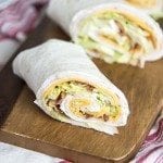 A close up of a turkey bacon ranch wrap on a piece of wood.