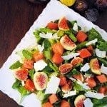 Above view of fig watermelon spinach salad on a square white plate.