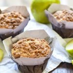 Angled view of apple crumb muffins in paper wraps.