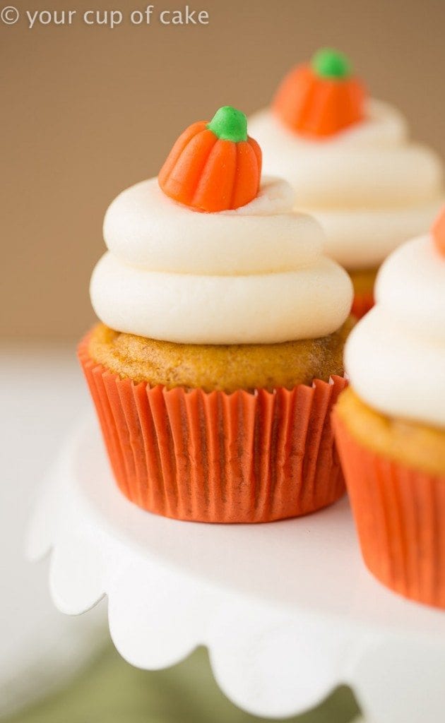 Side view of classic pumpkin cupcakes on a white plate with cream cheese frosting.