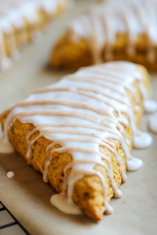 Close of of a pumpkin scone with frosting drizzled on top.