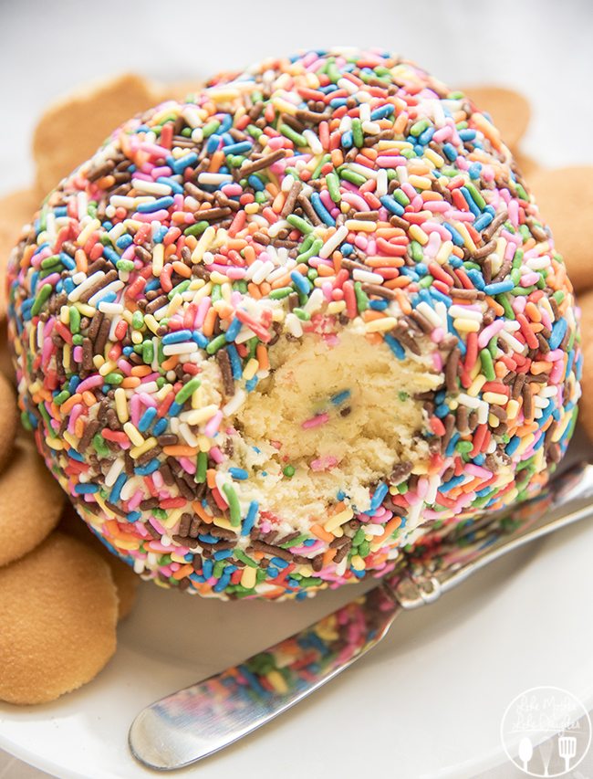 A sprinkle covered cake battery cheeseball is displayed with the middle visible.