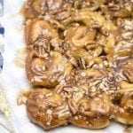 A close up of mini sticky pecan rolls topped with chopped pecans and caramel sauce.