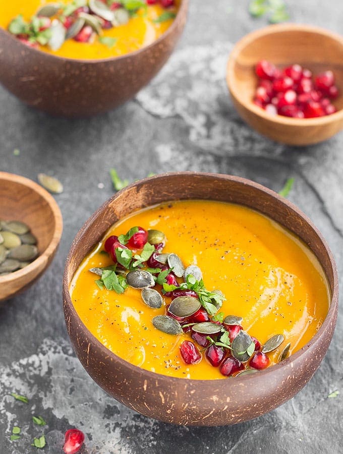 A bowl of roasted pumpkin apple soup is in a bowl on a table.