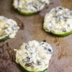 Close up view of zucchini spinach and artichoke dip bites on a wood board.