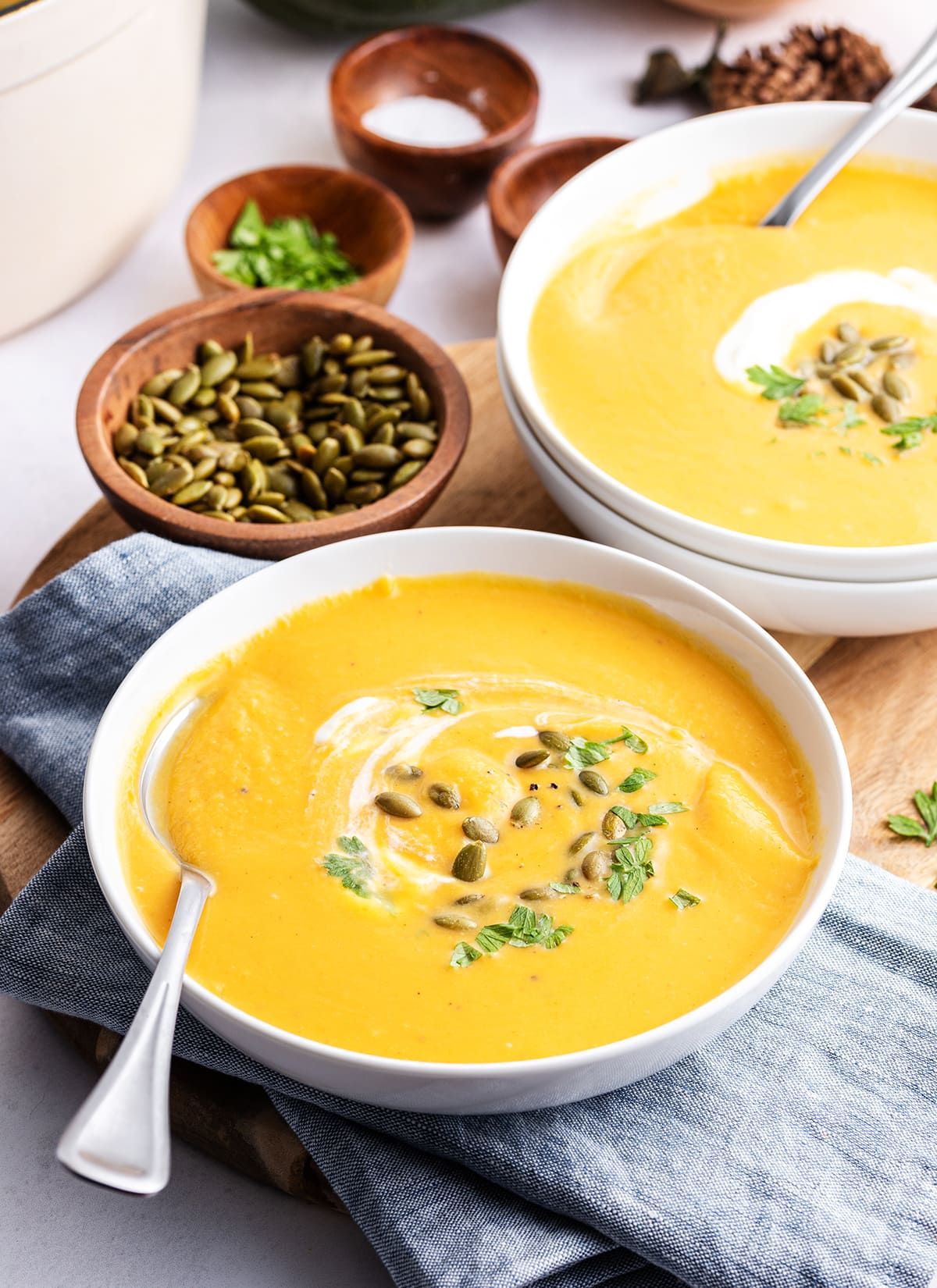 Two bowls of autumn squash soup with a spoon in them.