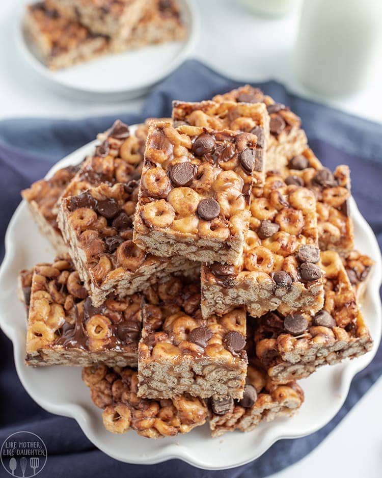 Close up image of many chocolate chip fluffernutter cheerio bars stacked on a plate in squares.