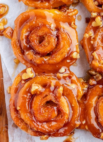 A close up of two mini caramel cinnamon rolls topped with pecans.