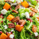 A close up of Roasted Butternut Squash Salad with feta and pomegranate pieces, and candied pecans.