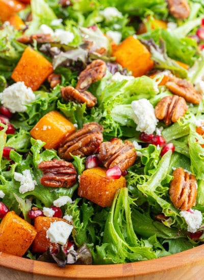 A close up of Roasted Butternut Squash Salad with feta and pomegranate pieces, and candied pecans.