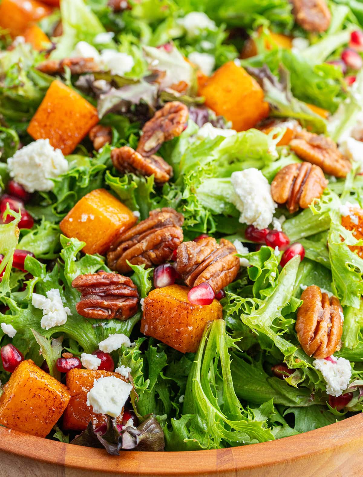 A close up of Roasted Butternut Squash Salad with feta and pomegranate pieces, and candied pecans.