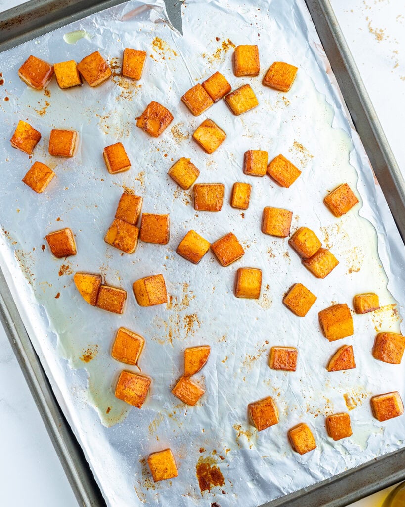 A baking pan with roasted pieces of butternut squash.