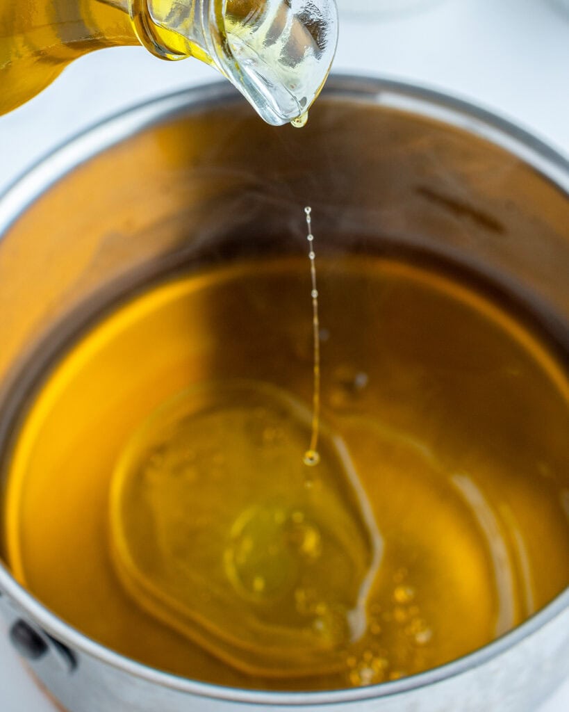 A pot of apple cider with olive oil being poured in