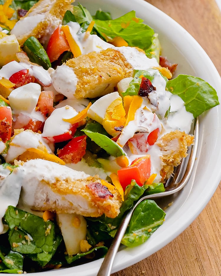 A close up of a chicken salad covered in ranch dressing.