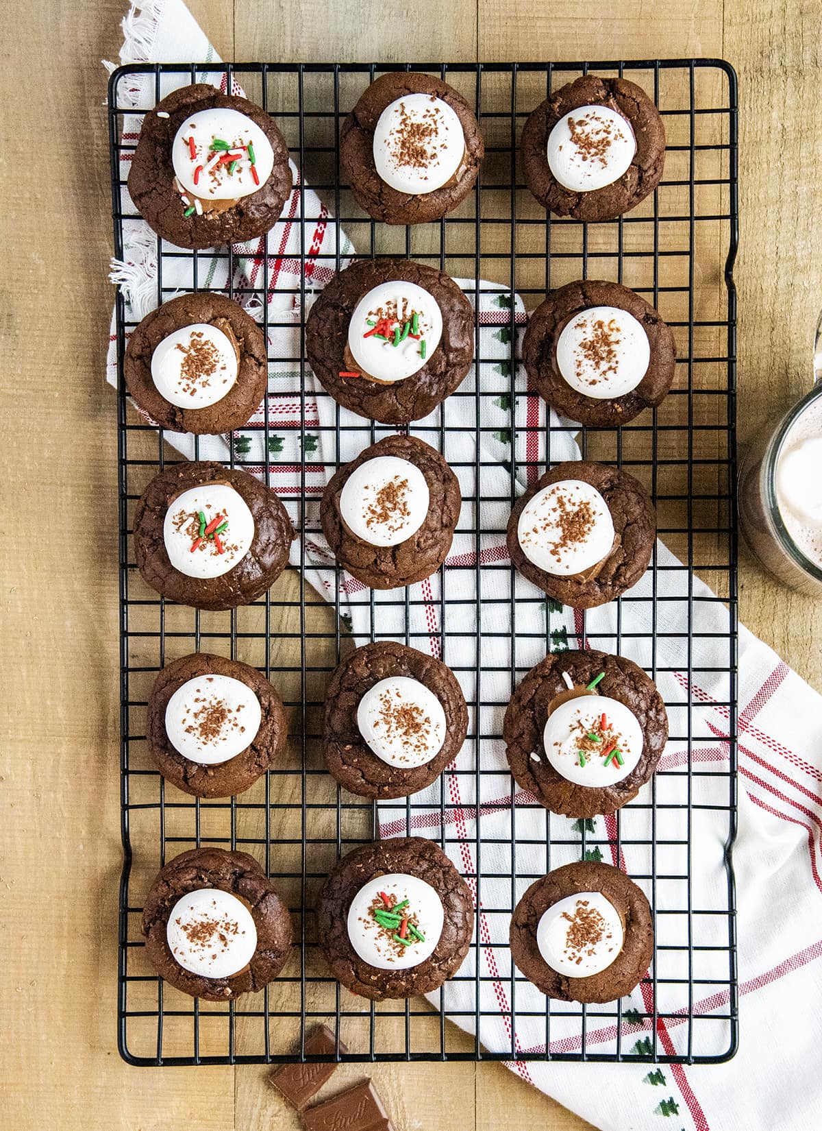 An overhead photo of a wire rack topped with hot chocolate cookies with marshmallows on top of each.