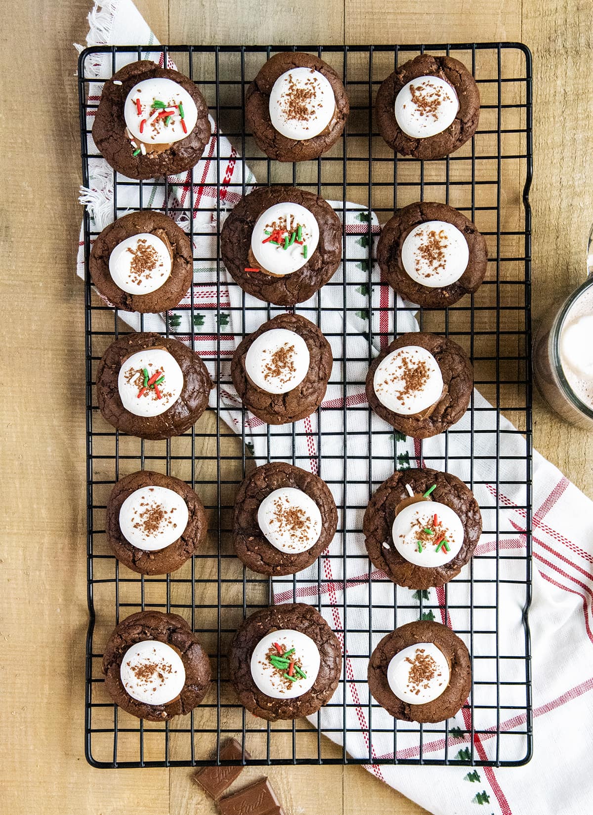 An overhead photo of a wire rack topped with hot chocolate cookies with marshmallows on top of each.