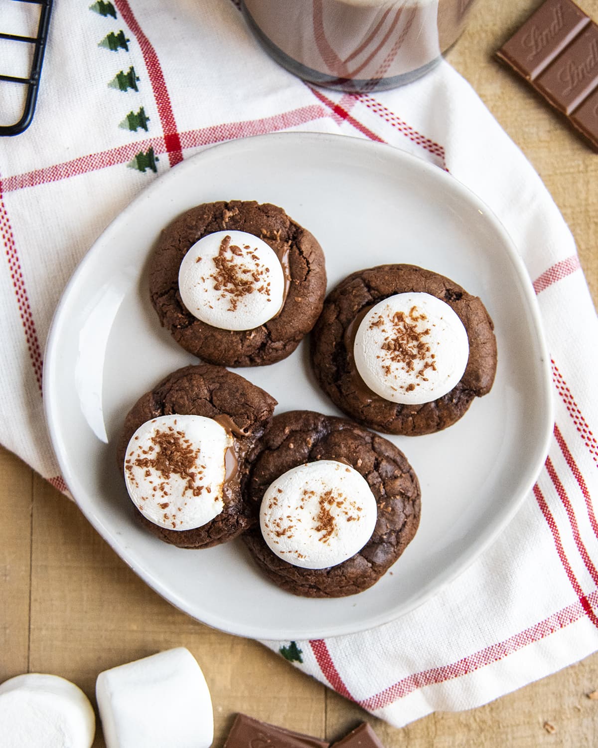 An overhead photo of a plate of 4 chocolate cookies topped with marshmallows on them. 