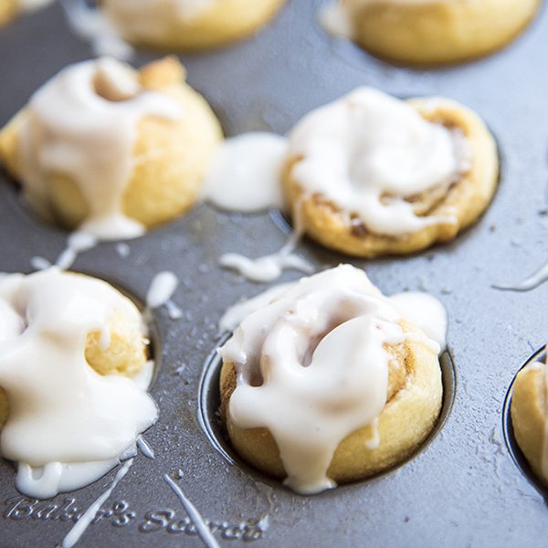 Close up view of mini cinnamon rolls in a baking pan.