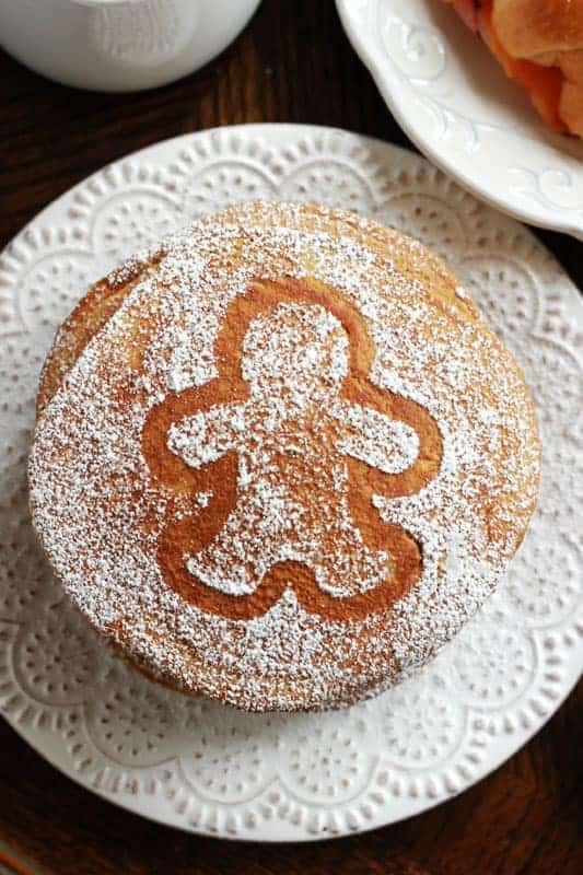 An overhead photo of a stack of gingerbread pancakes dusted with powdered sugar on top.