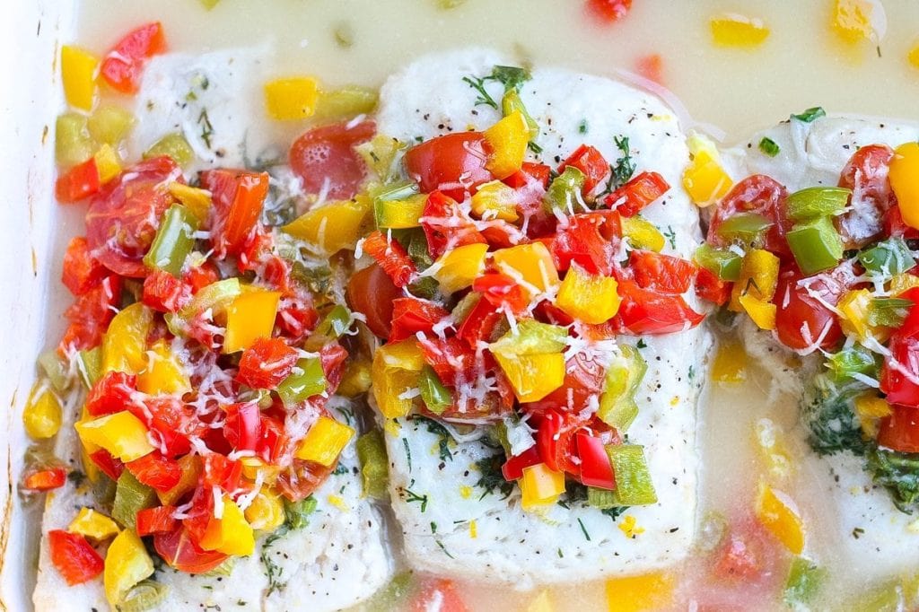 Three cooked halibut filets topped with bell peppers, tomatoes, and scallions and melted parmesan cheese.