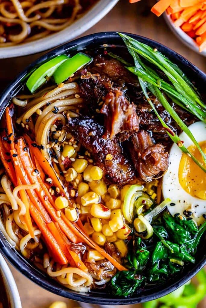 A bowl of pork ramen, with noodles, carrots, corn, egg, spinach, and more.