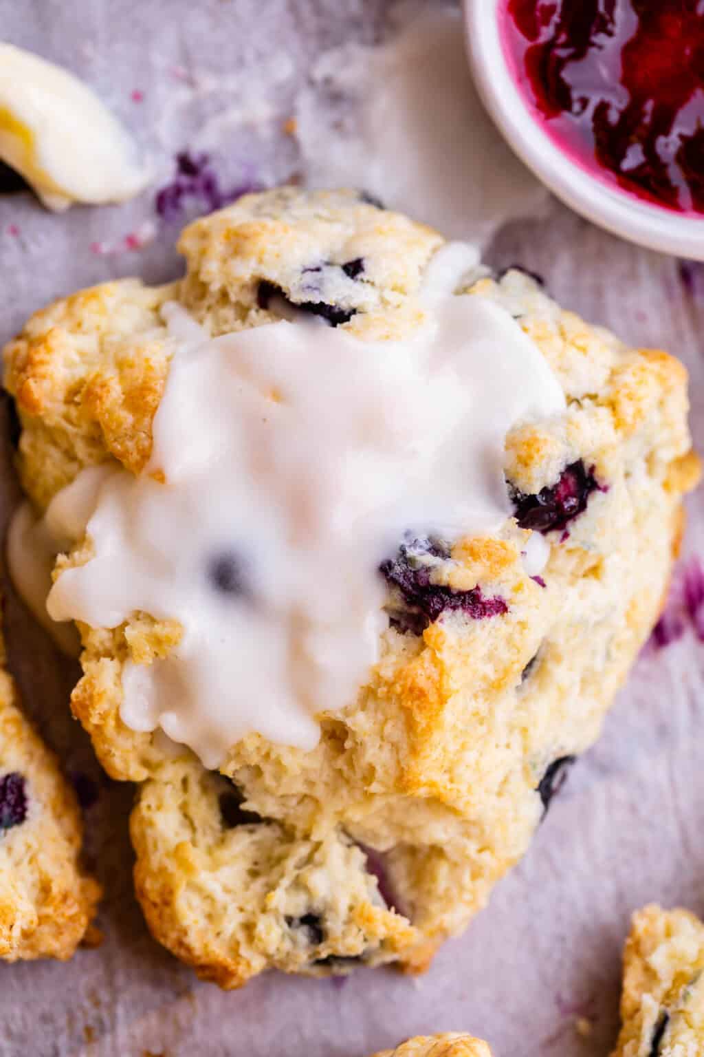 A close up of a blueberry scone with vanilla icing on top. 