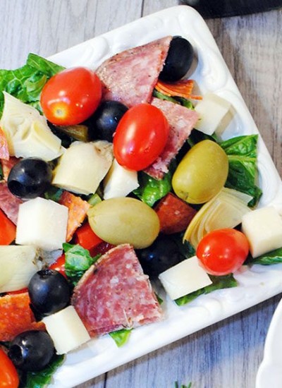 Angled view of antipasti salad on a square white plate.